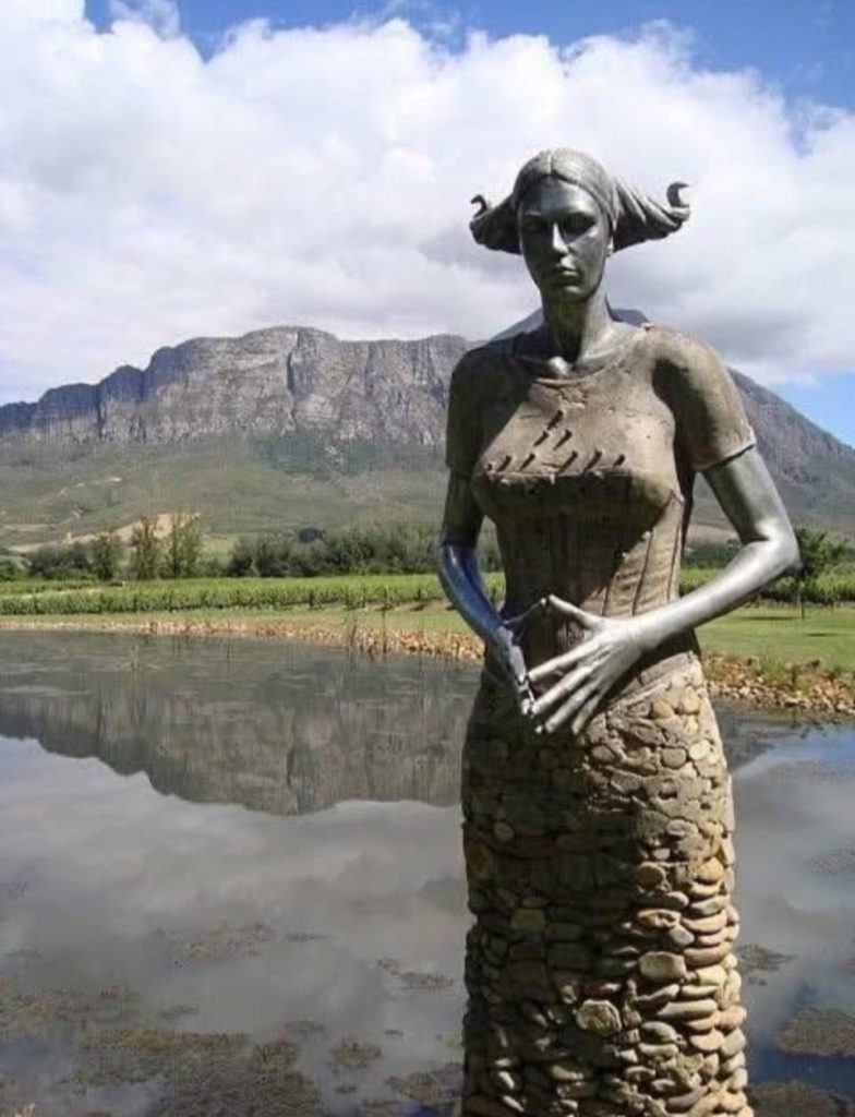 南非雕塑家Angus Taylor以花崗岩、紅碧玉和橘色礦土創作【石人大陣】沉默的巨人，透過「砌」而非「雕」的手法，保留石頭原貌象徵記憶與文化，呈現破碎與修復的後殖民社會隱喻。這些巨大石人彷彿承載歷史與土地的負擔，挑戰傳統束縛，讓人反思身份與文化根源，展現與土地共生的群體存在。