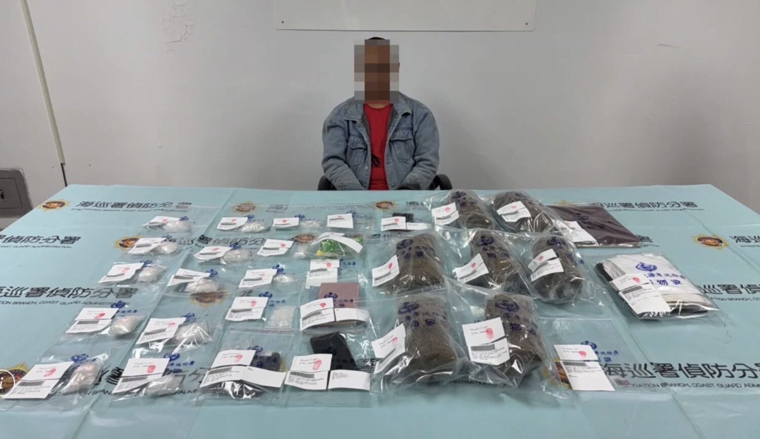 遭查獲的印尼籍逃逸移工「木奇」被帶回偵訊，桌面上陳列查扣的安非他命與大麻等證物，總重超過2公斤，全案依《毒品危害防制條例》移送橋頭地檢署偵辦。（圖／海巡署提供）