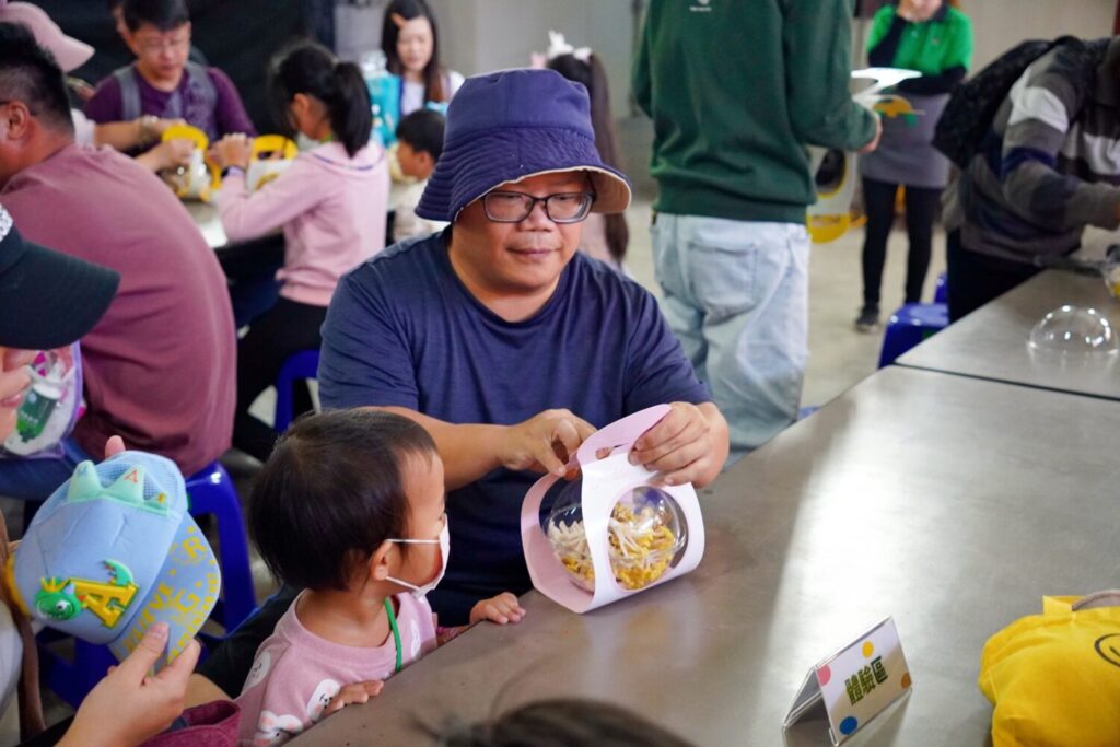 家長與孩子一同將親手採收的菇菇細心包裝，親子間的合作互動，為農場體驗增添更多溫暖記憶。（圖／豐年靈芝菇類生態農場）