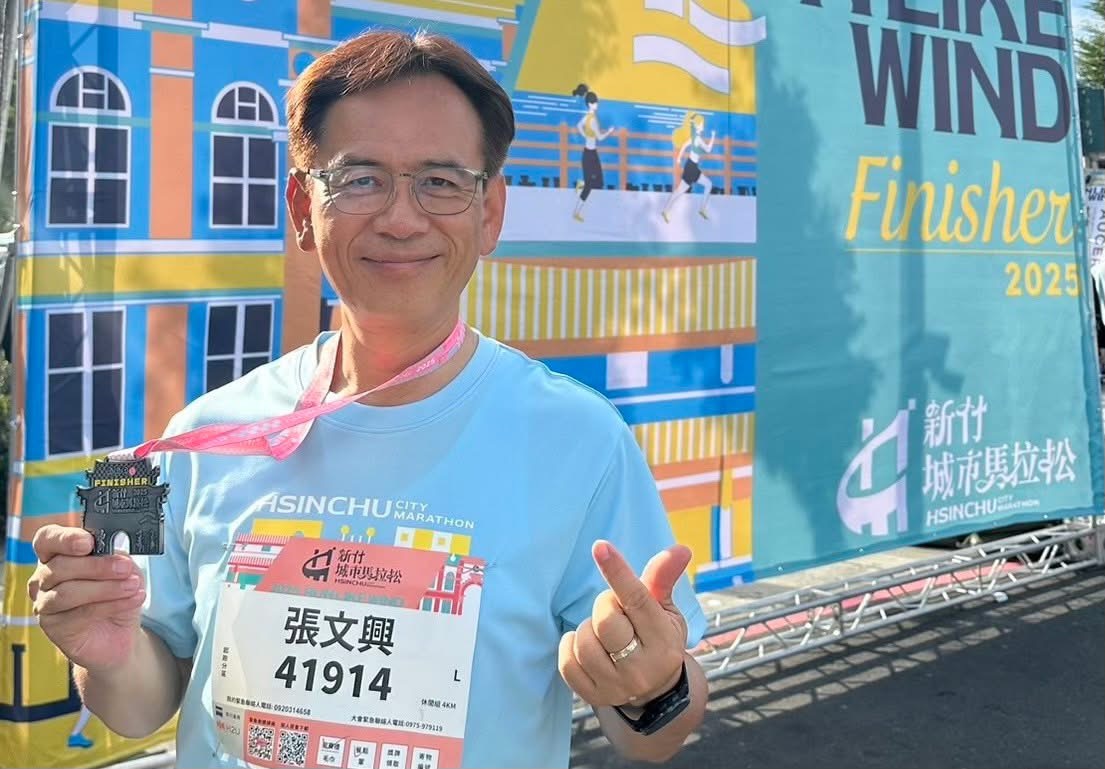 城市與跑者一同前進!張文興「路跑是新竹最美的凝聚力」 張文興理事長於 2025 新竹城市馬拉松順利完賽,並展示象徵賽事榮耀的迎曦門獎牌,背景為本屆大會主視覺,清晨陽光映照出路跑成就與城市活力。(圖/記者張家燁翻攝)