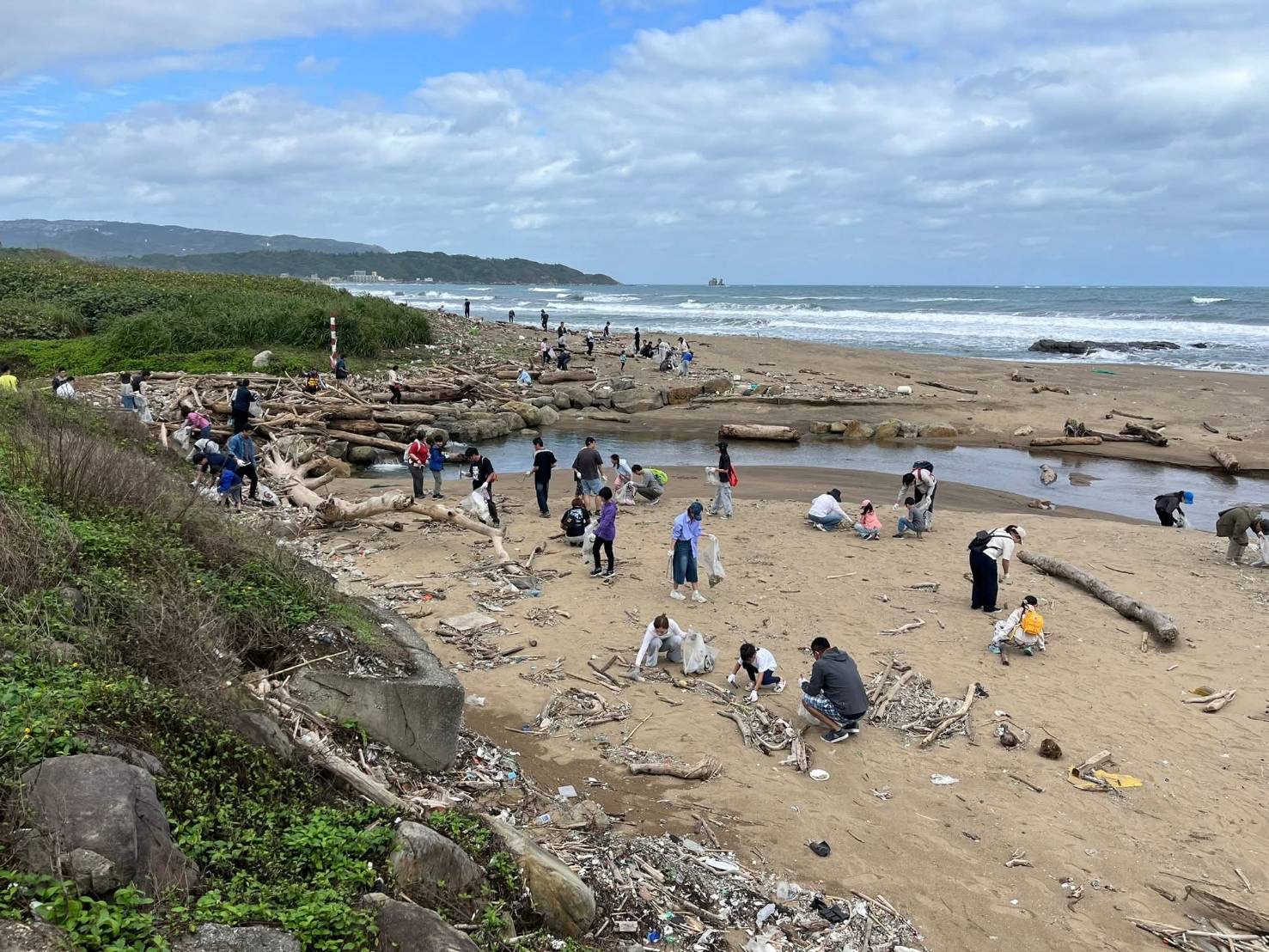 ESG 不只是口號!新創總會攜手企業清出 901 公斤海廢展現永續力 颱風過後的北海岸堆滿漂流物,各企業團隊與家庭成員分布海灘各處投入清理行動。(圖/新創總會提供)