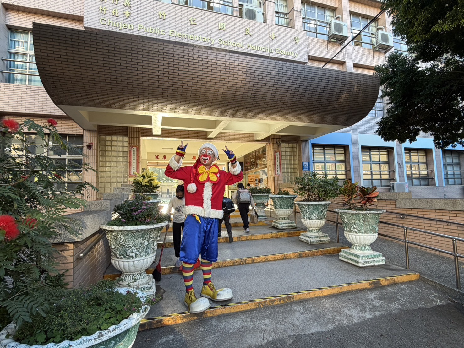 「迎接聖誕佳節」竹仁國小校園化身歡樂派對 聖誕節氣氛滿滿,魔術冠軍菲力以逗趣造型現身竹仁國小校門口,熱情迎接師生,為校園揭開歡樂聖誕活動序幕。(圖/記者張家燁拍攝)