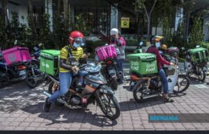 馬來西亞街頭外送騎士在餐飲門店外等候取餐。隨著《零工工作者法案2025》通過，外送騎士的服務協議、報酬資訊與爭議處理機制將被納入更明確的法制規範，也意味著仰賴外送衝尖峰的連鎖餐飲業者，未來在出餐流程、合作條款與責任切割上，需面對更高的合規與管理要求。圖為示意畫面。（翻攝自 BERNAMA）