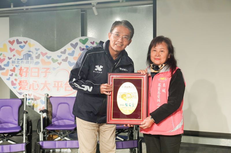 善心企業團體讓愛輪轉 9單位合捐新北305台輪椅 40 《圖說》新北市府秘書長邱敬斌(左)代表侯友宜市長回贈感謝牌給土城鳳靈慈愛同心會理事長黃妙鳳。〈社會局提供〉