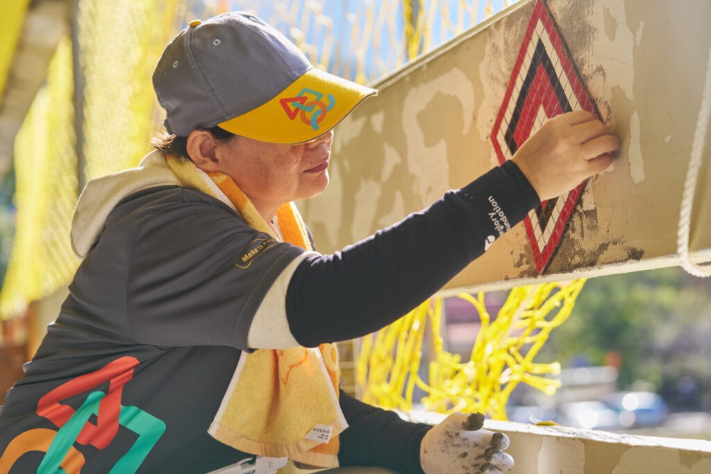 「祖靈之眼」守望校園 遠雄志工入山協助翻新桃山國小 遠雄志工在二樓女兒牆,利用馬賽克磚貼上代表泰雅族文化的「祖靈之眼」。(圖/遠雄文教公益基金會 提供)