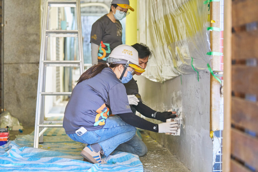 「祖靈之眼」守望校園 遠雄志工入山協助翻新桃山國小 刨除剝落的牆面舊漆後進行丕土,以便後續上漆時的牆面平整。(圖/遠雄文教公益基金會 提供)