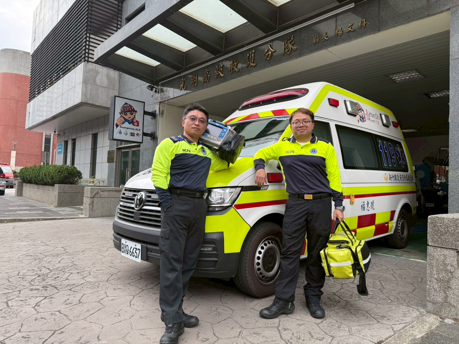 「大新竹首例院前葉克膜啟動」警消醫聯手救回36歲男子 新竹縣政府消防局光明高救隊資深高級救護技術員李均祈(左)、許嘉雄(右),為此次新竹縣首例院前葉克膜成功搶救的重要關鍵人物,於分隊前與救護車合影,展現第一線救護專業與守護生命的使命感。(圖/記者張家燁翻攝)