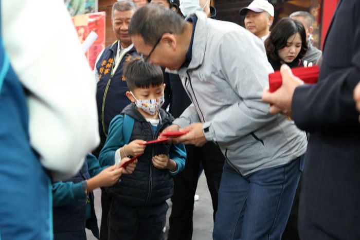 大年初二蘆洲祈福參拜 侯友宜邀出外賞燈踏青走春 30 《圖說》侯友宜市長與小朋友介紹馬年福袋上面的祝福寓意。〈民政局提供〉