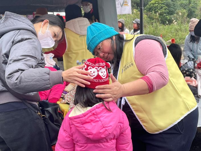 實質關懷19年 淡水區關懷弱勢協會席開百桌春節送暖 20 《圖說》新北市淡水區關懷弱勢協會串連民間資源捐贈物資和善款,龍巖慈善基金會提供保暖衣物,協助民眾穿戴毛帽。〈社會局提供〉