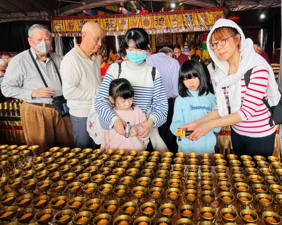覺行寺初六舉行動工大典 萬燈供佛祈福法會圓滿 17 《圖說》2026新春萬燈供佛法會,媽媽帶著小孩子同沾法喜點燈祈求吉祥光明。〈主辦單位提供〉