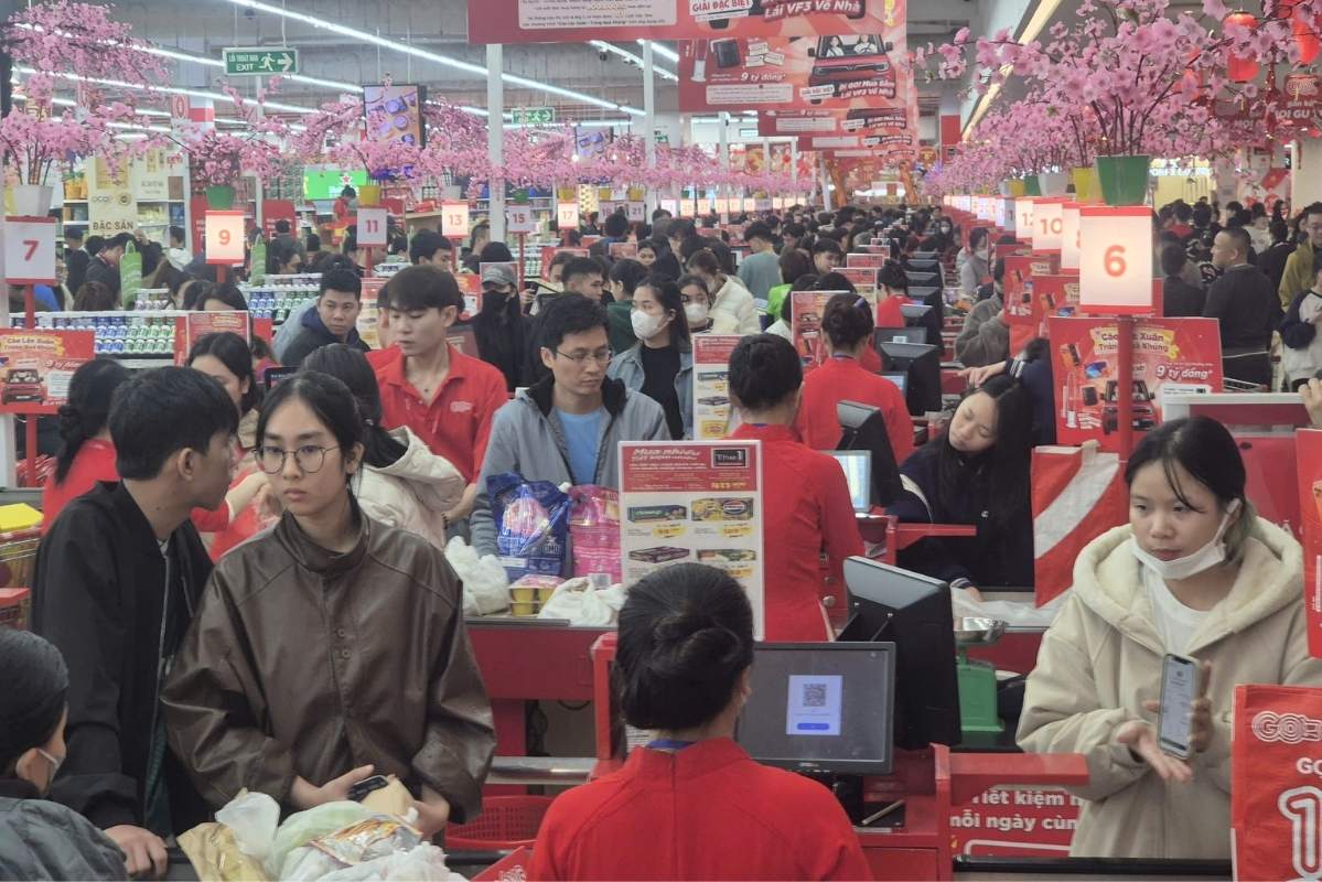 越南超市於2026年農曆新年前夕湧現採購人潮，顧客在收銀台前等待結帳。零售商表示春節期間客流量與銷售額較促銷初期成長兩至三成。圖片來源：越南勞動報（Lao Động）