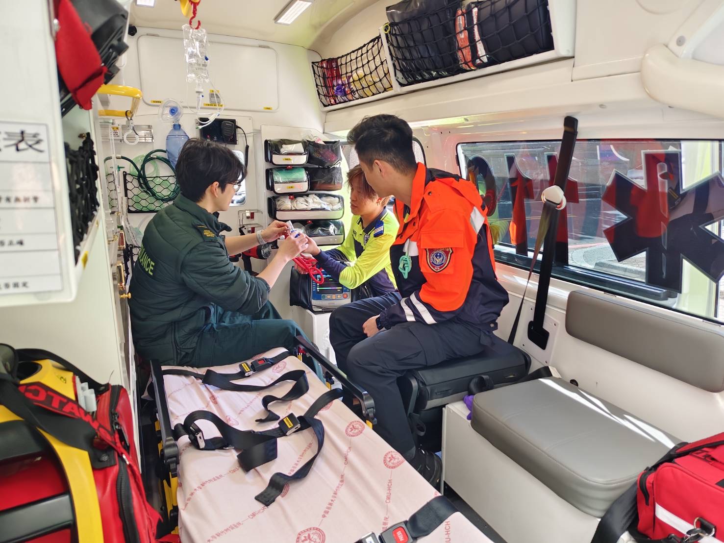 「台英救護制度交流」英國救護員盛讚竹縣OHCA救護成效 英國南中央救護服務(SCAS)救護員莊家豪教官(左)於救護車內與新竹縣消防局救護人員進行到院前救護器材與處置技術交流。(圖/記者張家燁翻攝)