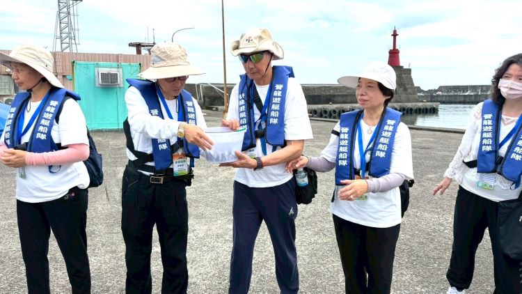 靈鷲山基隆嶼放流2.4萬尾魚苗 淨灘清出142公斤垃圾 36 《圖說》大家將魚苗置於水桶中,精準掌握時間、角度與力道接力傳遞,讓魚苗平安回歸大海。(靈鷲山佛教教團提供)