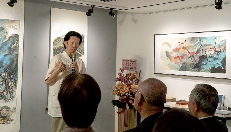 以藝載道照萬象 明月法師畫展揭生命澄明之境 9 《圖說》劉易齋教授解說明月師的魚游自在、荷花清淨的超脫俗塵畫作。〈主辦單位提供〉