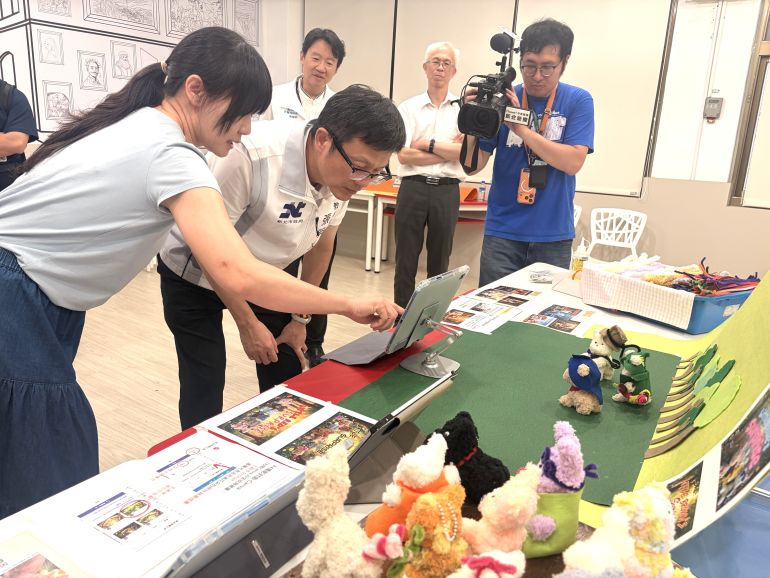 新北培育STEAM夢想推手 授證12位種子教師 12 《圖說》陳品璇老師向局長示範藝術手作與AI工具應用結合產出如同電影海報般的作品,每個學生都可以學習使用AI工具讓自己的作品有不同呈現的樣貌。〈教育局提供〉