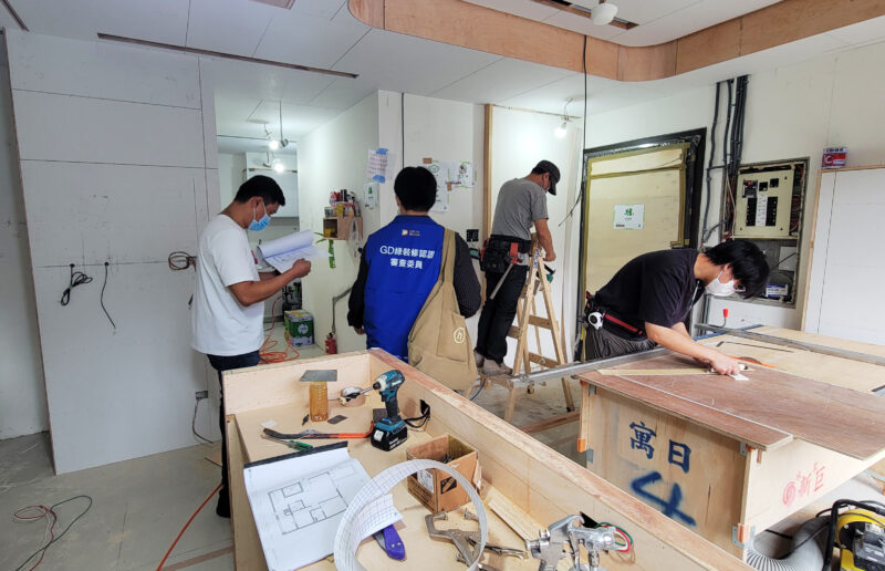 室內設計公司的工程管理在做什麼?施工期間可以確認的5件事 施工中的室內現場,身穿GD綠裝修認證審查委員背心的人員與手持圖面的現場人員、木作工班同在工地