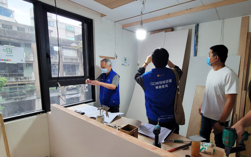 室內設計公司的工程管理在做什麼?施工期間可以確認的5件事 施工中的窗邊貼有保持通風標示,牆面貼有建材堆放整齊標示,審查委員背心人員與工班在現場查看