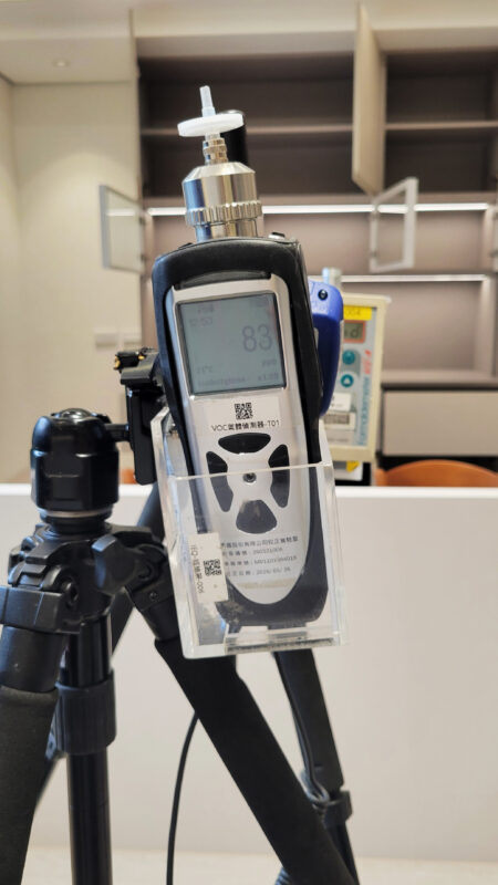 室內設計公司的工程管理在做什麼?施工期間可以確認的5件事 腳架上的VOC氣體偵測器螢幕顯示83 ppb,背景為櫃門打開的客廳空間